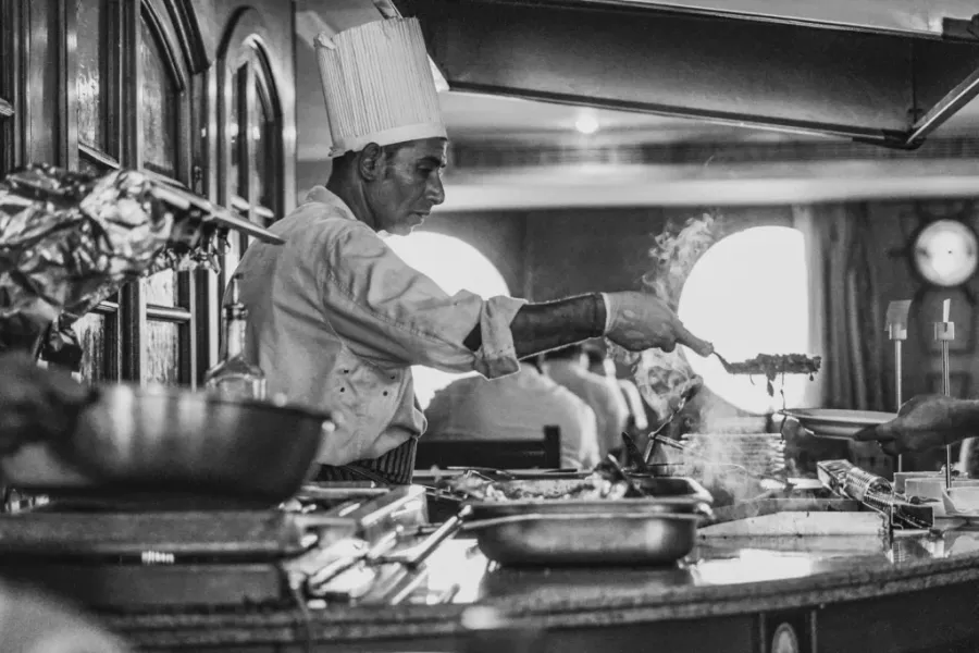 grayscale photo of man cooking - libros de cocina clásicos